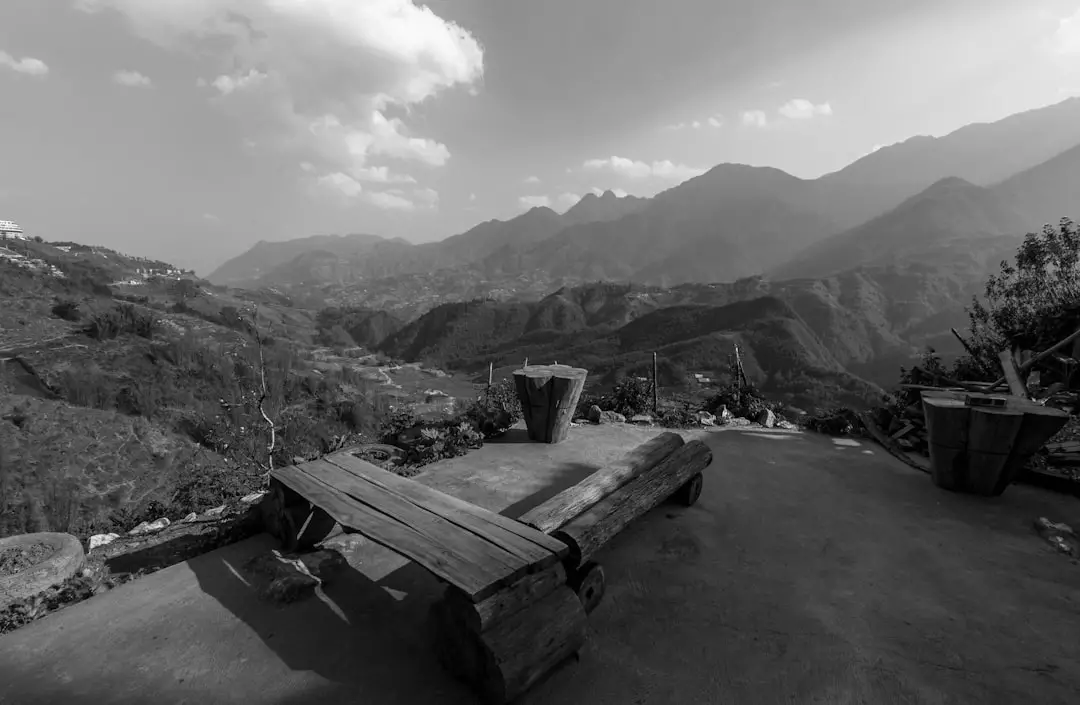 a black and white photo of a bench and mountains