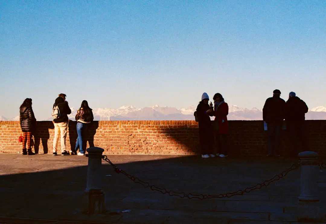 People enjoying the view in Torino, Italy. by Walkathon Virtual A group of people standing on top of a brick wall