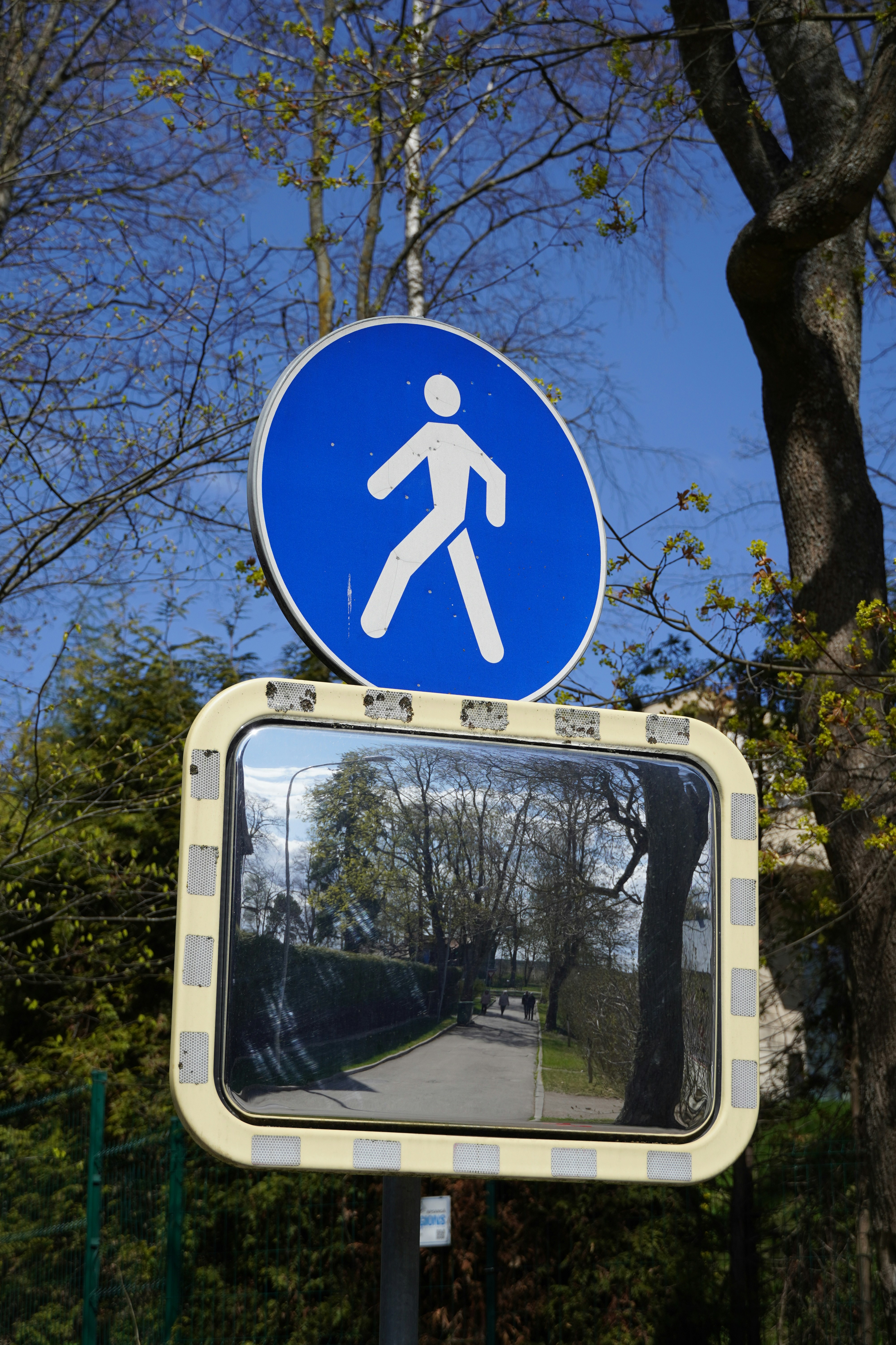 a mirror showing a person walking on a street